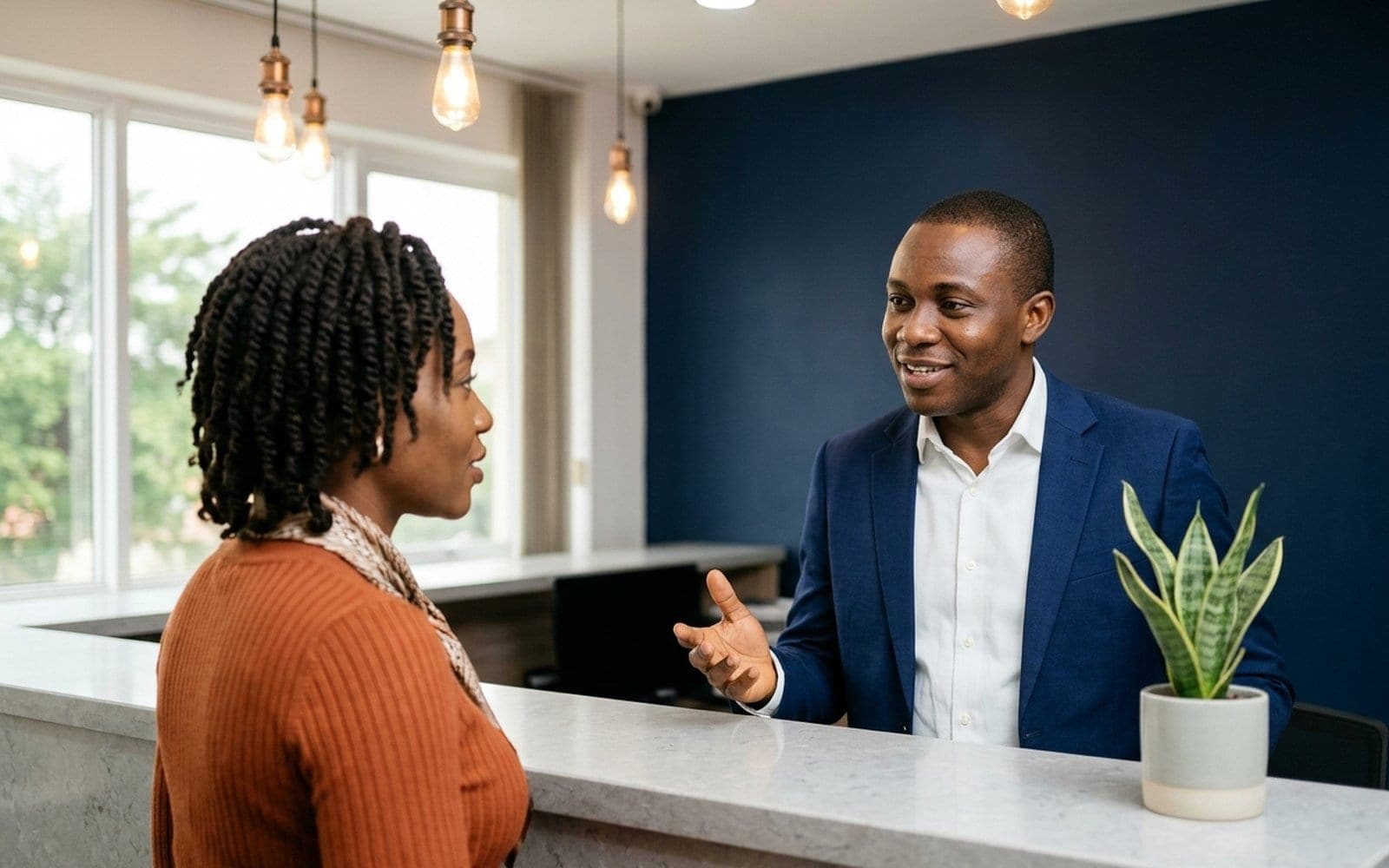 A customer and a staff member talking across a desk in a calm, bright office.